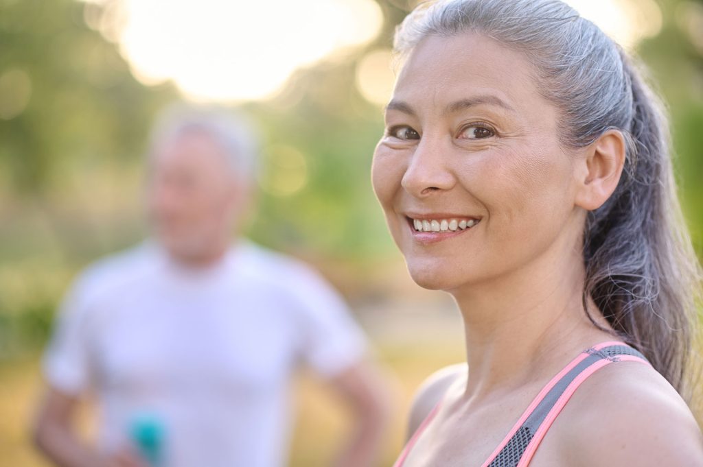 Mature fit woman, together with a blurred mature man.