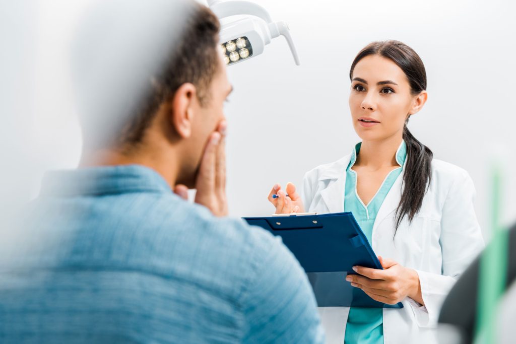 Selective focus of female dentist talking to a patient.
